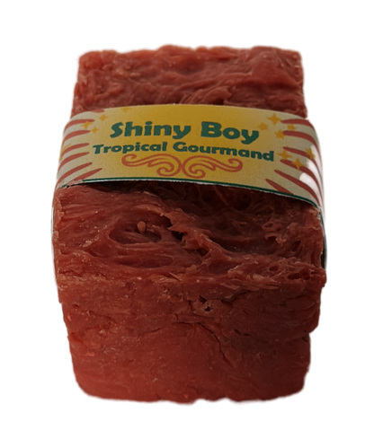 Coral-rose handmade soap bar with swirled rustic texture, wrapped in a vintage carnival-style yellow and cream band reading "Shiny Boy – Tropical Gourmand"