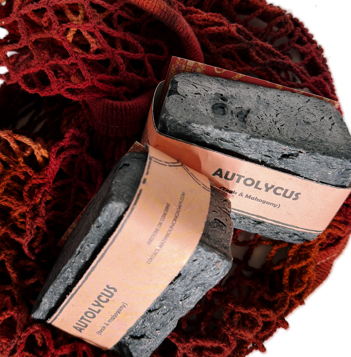Assorted Bouncing Studio handmade bar soaps in a red rope basket including black bar of Autolycus soap